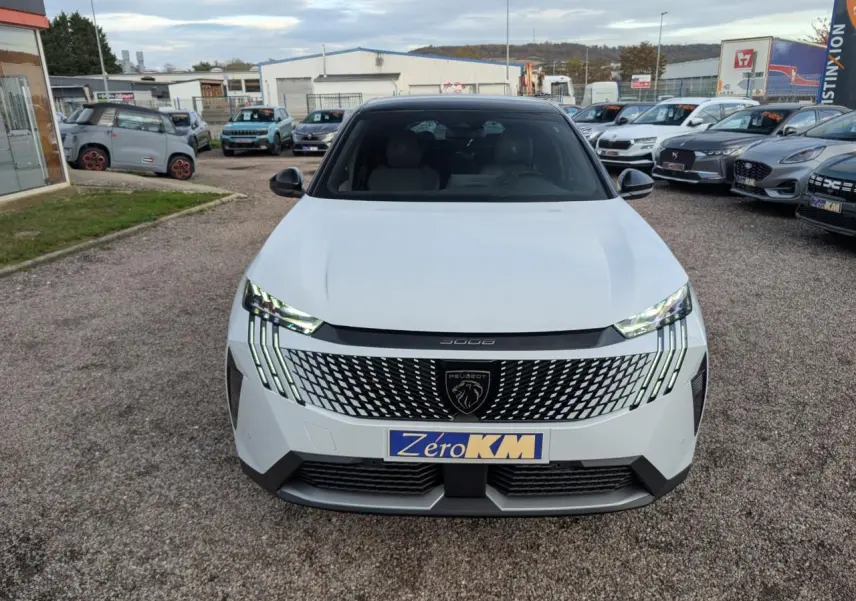 Vue avant d'un Peugeot 3008 blanc 2025 avec calandre noire à motif géométrique et feux LED griffés.