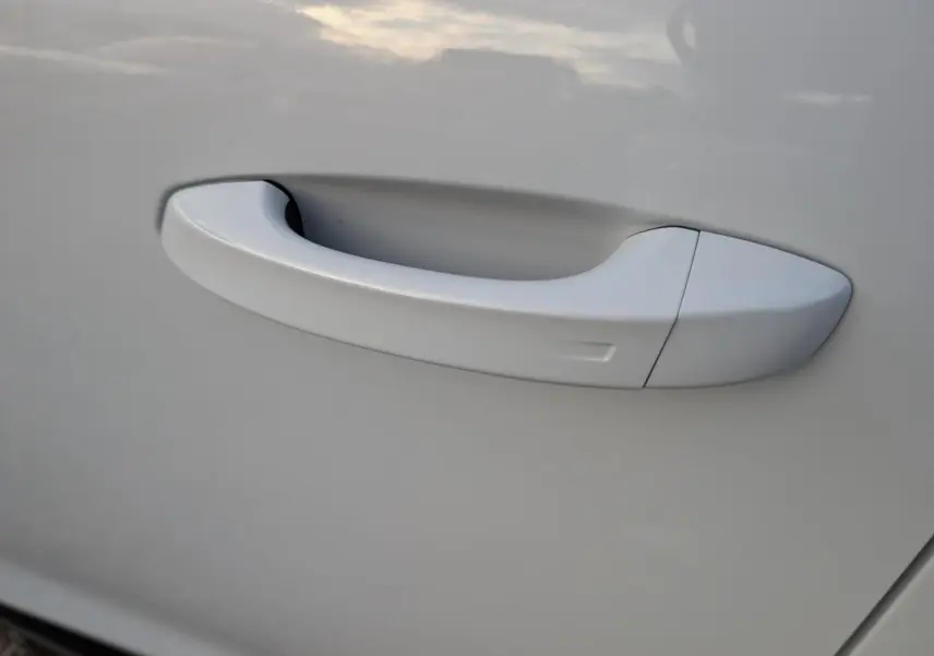 Poignée de porte blanche en gros plan sur Peugeot 3008 1.2i Hybrid GT 2025, finition lisse et intégrée.