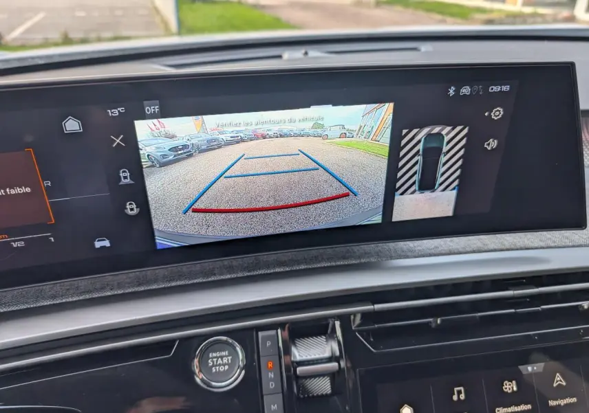 Vue intérieure sur l'écran tactile affichant la caméra de recul du Peugeot 3008 blanc, avec commandes et bouton start visibles.