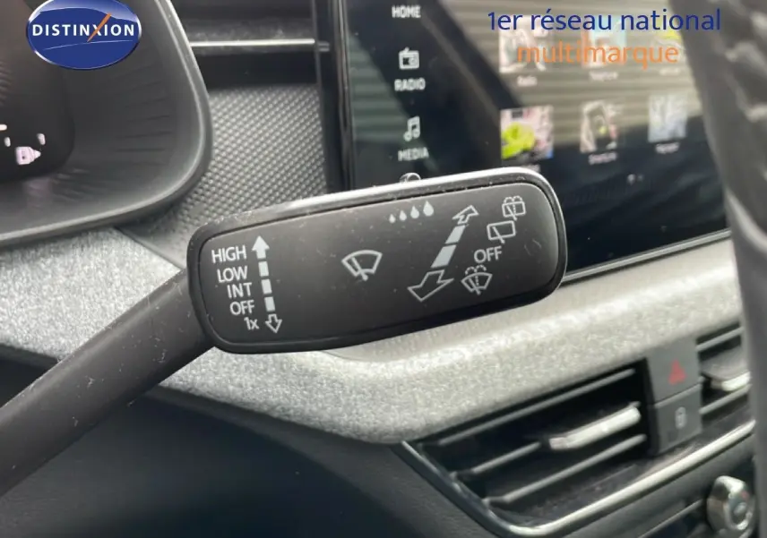 Gros plan sur la commande d’essuie-glace à gauche du volant dans l’habitacle gris noir d’une Skoda Scala noir magique métal.