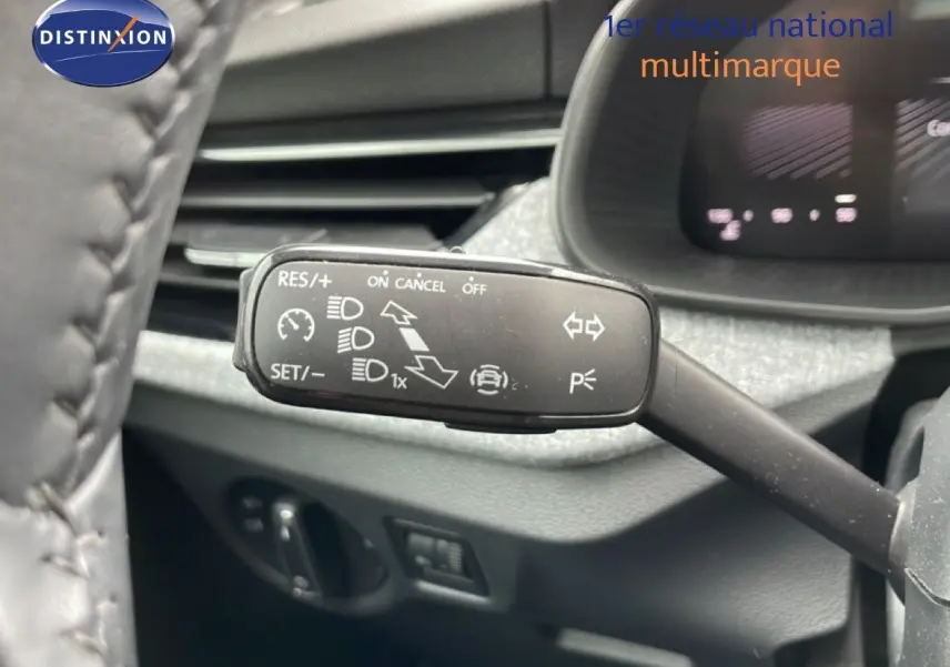 Gros plan sur la commande de régulateur de vitesse à gauche du volant dans l’habitacle gris noir d’une Skoda Scala noir magique métal.