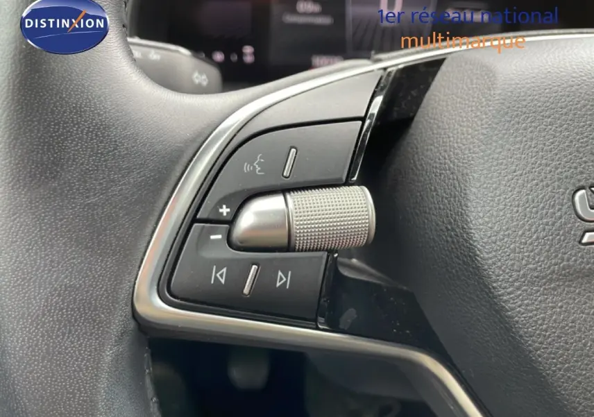 Gros plan sur les commandes gauche du volant en cuir noir d’une Skoda Scala 2025, avec molette métallique texturée.