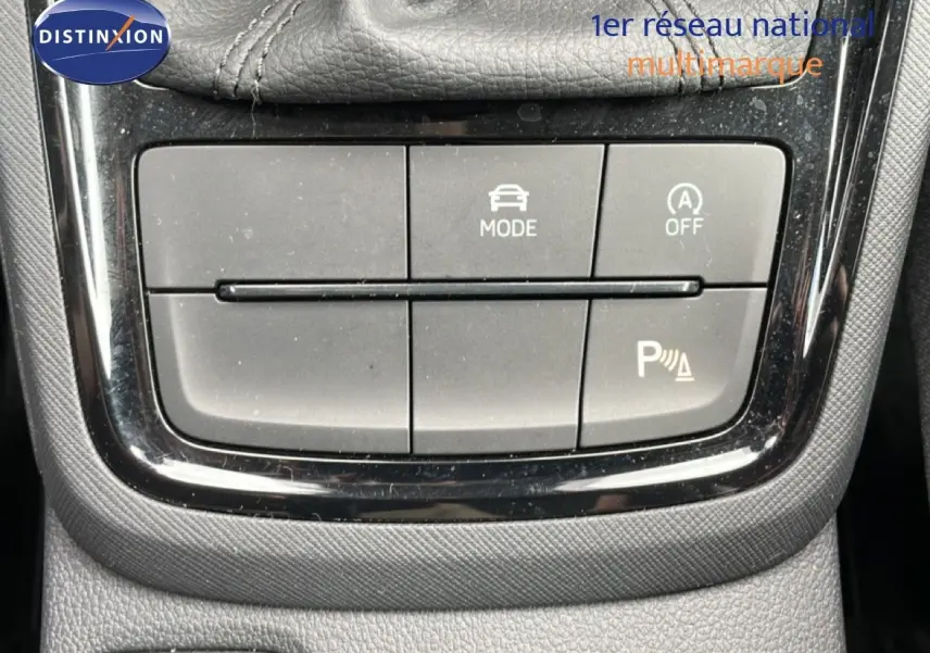 Gros plan sur les boutons de commande du mode de conduite et assistance parking d'une Skoda Scala noire.