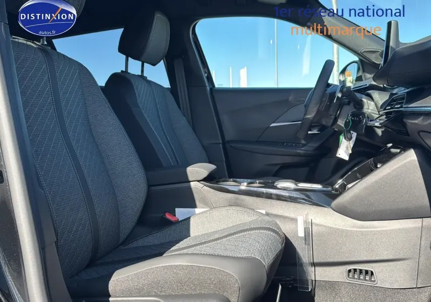 Intérieur de la Peugeot 2008 1.2 hybrid 145 allure 2025, vue côté conducteur, sièges tissu gris et tableau de bord moderne.