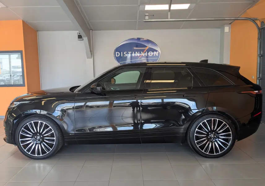 Profil côté gauche du Range Rover Velar noir 2020 avec jantes alliage bicolores et toit panoramique en showroom.