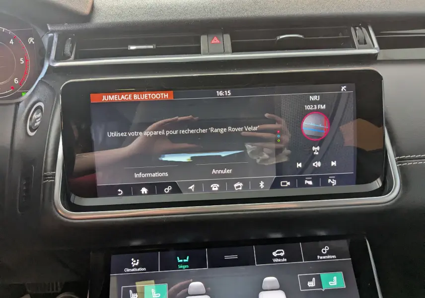 Vue rapprochée de l’écran tactile central du Range Rover Velar 2020 noir affichant le jumelage Bluetooth et les réglages des sièges.