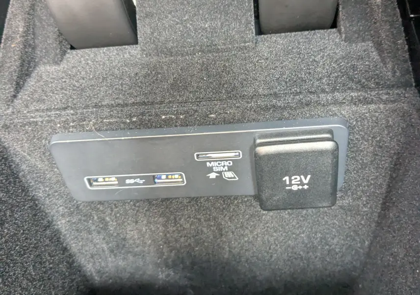 Gros plan sur la prise 12V et ports USB avec emplacement micro SIM dans l'habitacle noir du Range Rover Velar 2020.
