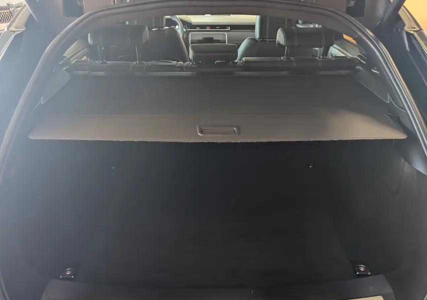 Coffre ouvert vu de l'arrière d'un Range Rover Velar noir 2020, avec cache-bagages et intérieur cuir noir visible.
