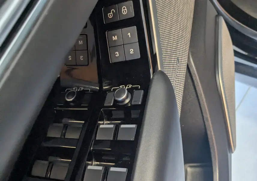 Gros plan sur la commande des vitres et mémoires de siège côté gauche d’un Range Rover Velar noir 2020.