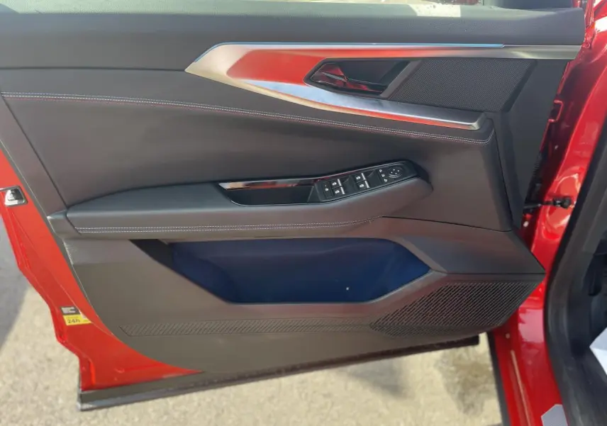 Gros plan sur la porte avant gauche rouge du Renault Rafale Esprit Alpine, avec commandes de vitres et surpiqûres blanches.
