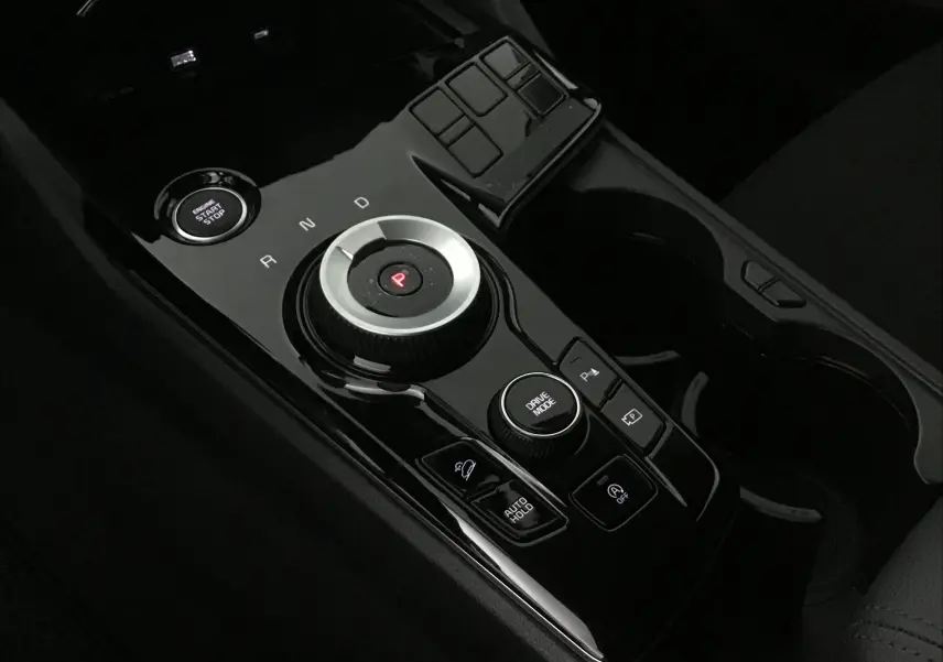 Vue rapprochée de la console centrale noire du Kia Sportage 2025 avec molette de boîte auto et bouton start/stop.