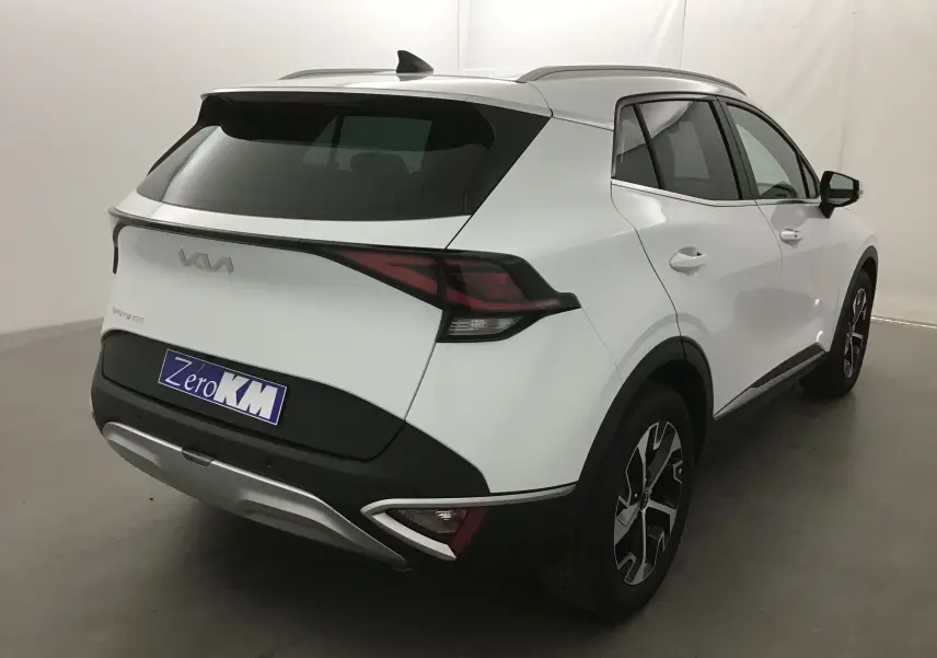 Vue 3/4 arrière droite d'un Kia Sportage blanc 2025 avec feux arrière LED et jantes alliage noires.