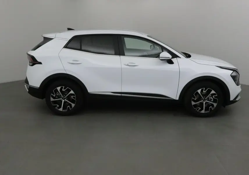 Profil côté droit du KIA SPORTAGE blanc 2025 avec jantes noires et détails noirs contrastants.