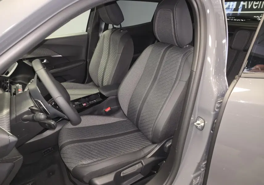 Vue intérieure côté conducteur du PEUGEOT 2008 gris 2025, mettant en valeur les sièges tissu et TEP avec surpiqûres Quartz.