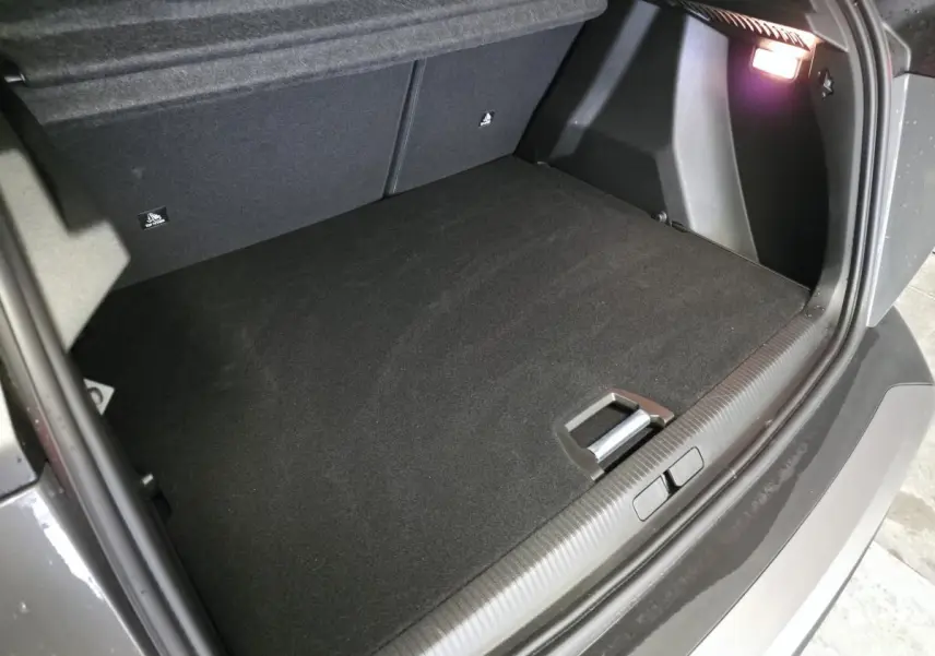Vue intérieure du coffre spacieux et propre du Peugeot 2008 gris, éclairé par une lampe intégrée sur le côté droit.