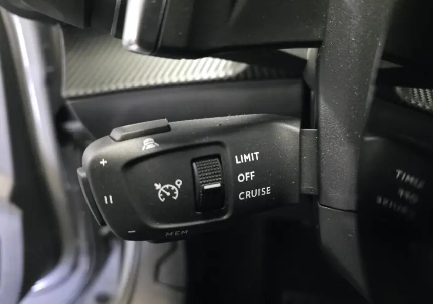 Gros plan sur la commande de régulateur de vitesse du Peugeot 2008 gris, située derrière le volant à gauche.