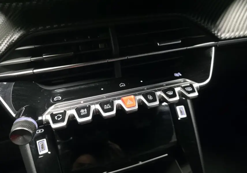 Gros plan sur la console centrale noire brillante du Peugeot 2008 2025 avec boutons de commande et prises USB type C.