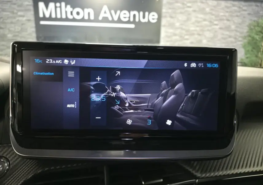 Écran tactile intérieur affichant la climatisation de la Peugeot 2008 1.2i Hybrid 2025 avec vue latérale des sièges noirs.