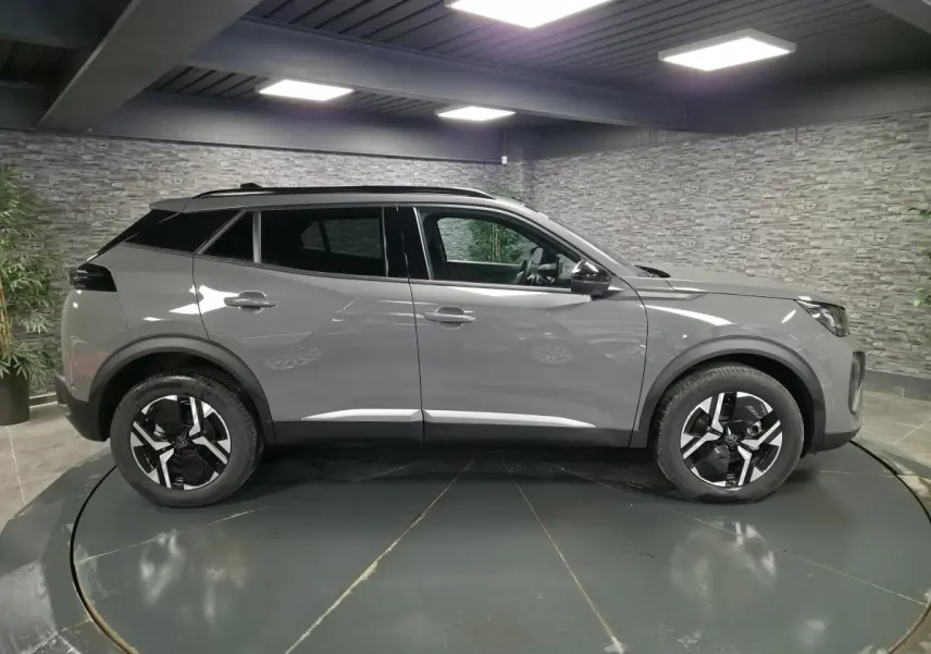 Vue latérale droite du Peugeot 2008 gris métallisé 2025 avec jantes alliage bi-ton et toit noir contrasté.