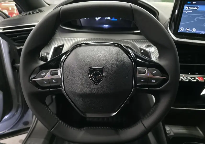 Vue rapprochée du volant compact noir de la Peugeot 2008 2025 avec commandes multimédia intégrées.