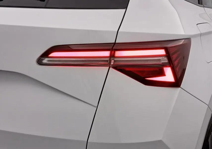 Gros plan sur le feu arrière droit allumé d’un Skoda Karoq blanc lune, soulignant les lignes anguleuses du coffre.