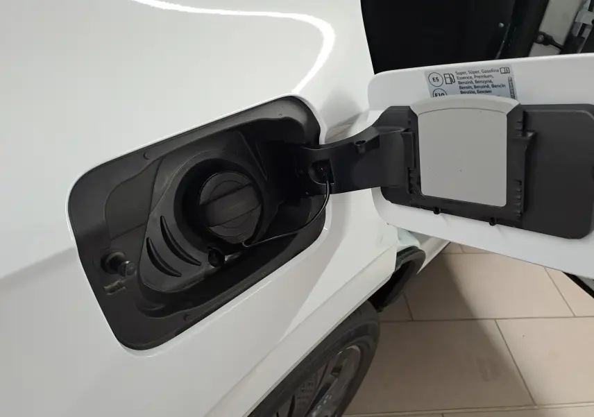 Gros plan sur la trappe à carburant ouverte côté gauche d’un Skoda Karoq blanc lune, essence, 2025.