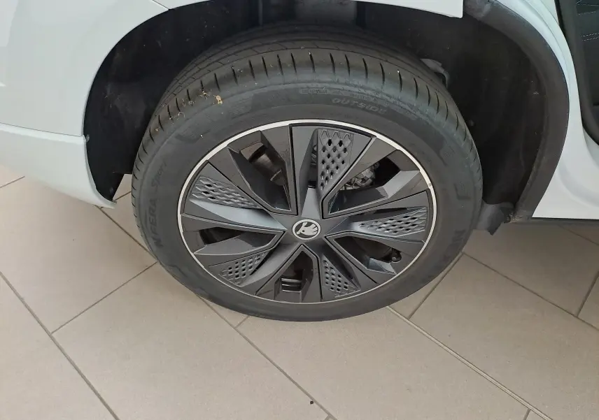 Gros plan sur la roue avant gauche du Skoda Karoq blanc Lune, mettant en valeur la jante noire au design moderne.