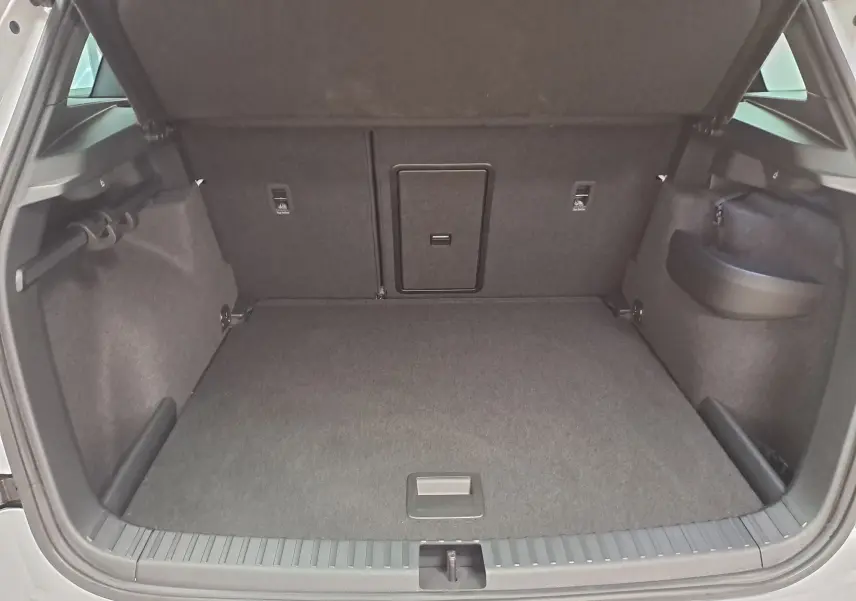 Coffre ouvert vu de l'arrière d'un Skoda Karoq blanc lune, montrant un espace de chargement propre et spacieux.