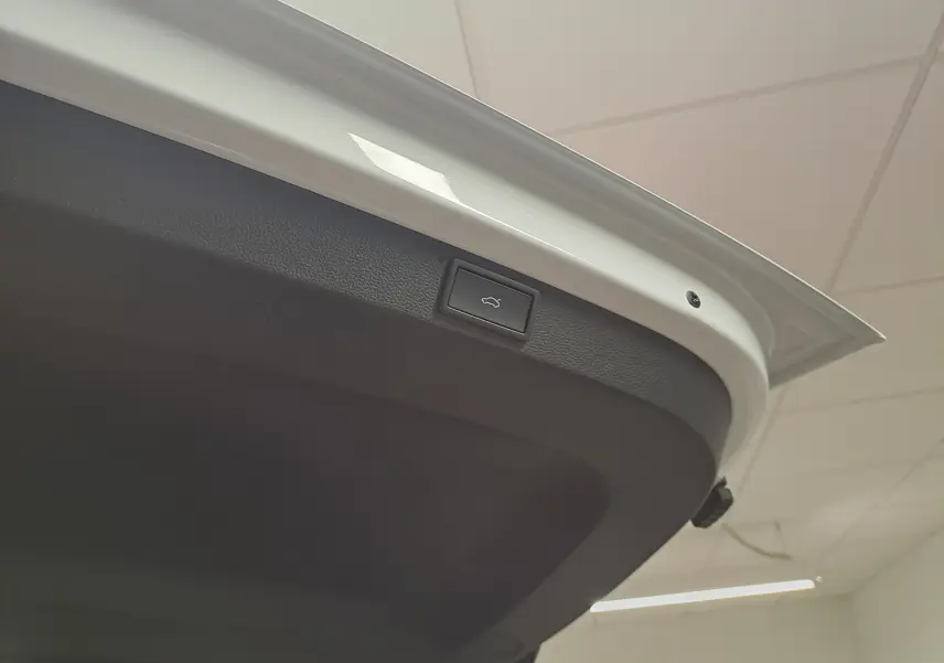 Bouton d'ouverture électrique du hayon sur la face intérieure du coffre d'un Skoda Karoq blanc lune.