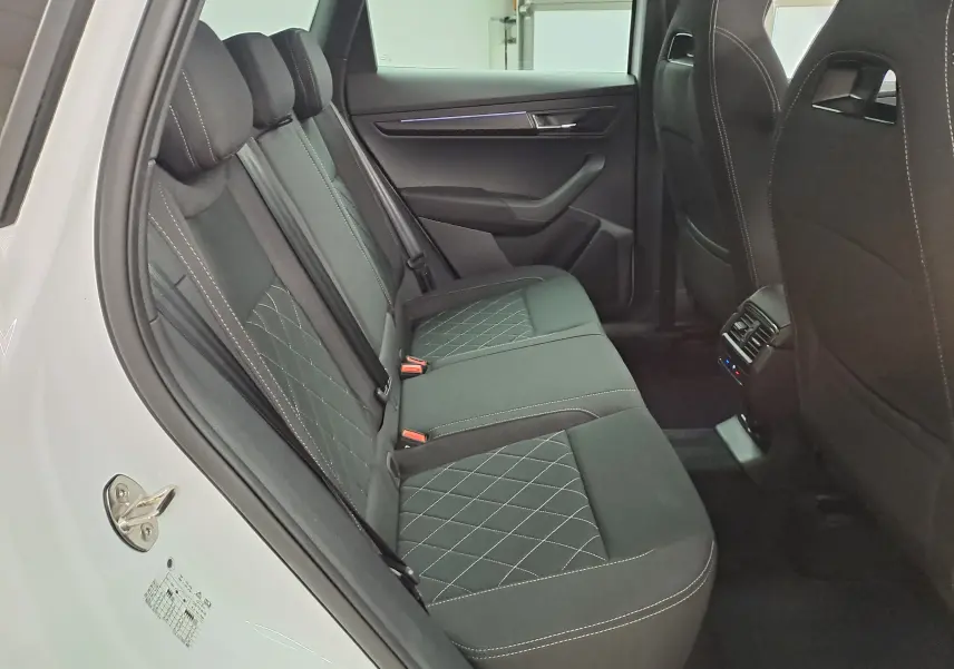 Vue intérieure côté gauche des sièges arrière noirs avec surpiqûres blanches du Skoda Karoq blanc lune 2025 Sportline.