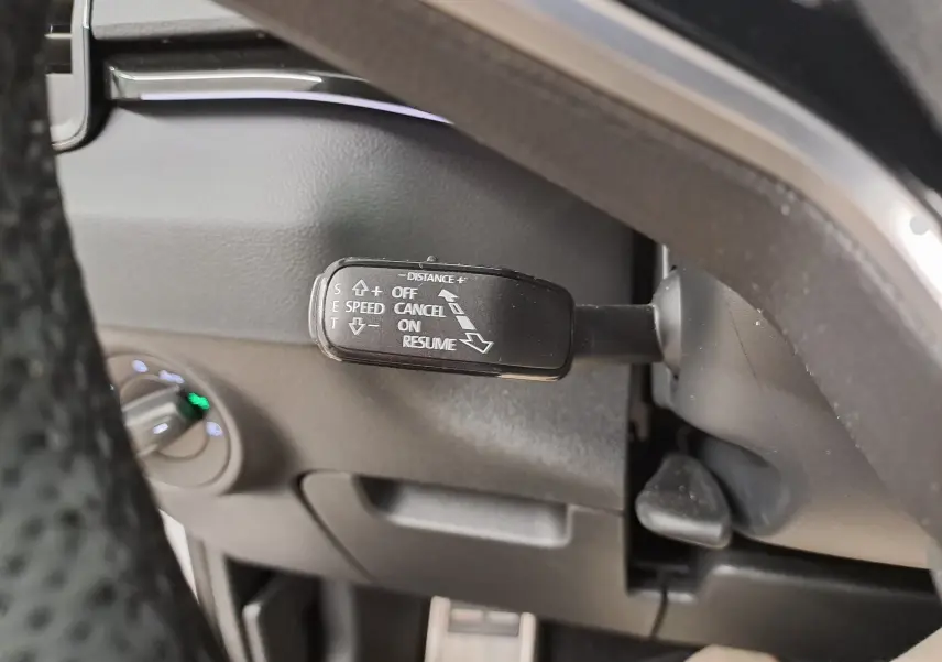 Gros plan sur le commodo de régulateur de vitesse du SKODA KAROQ 1.5 TSI 150 DSG7, intérieur noir.