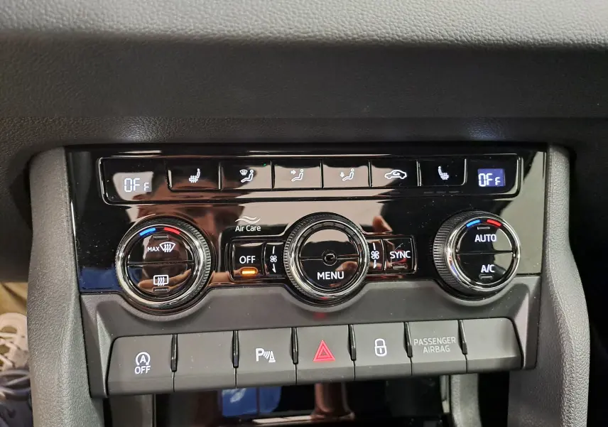 Gros plan sur la console centrale du Skoda Karoq blanc lune 2025, avec commandes de climatisation tri-zone et boutons fonctionnels.