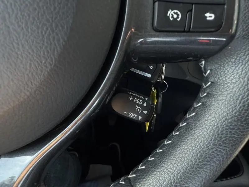 Gros plan sur le levier de régulateur de vitesse derrière le volant cuir de la Toyota Yaris gris métal 2020.