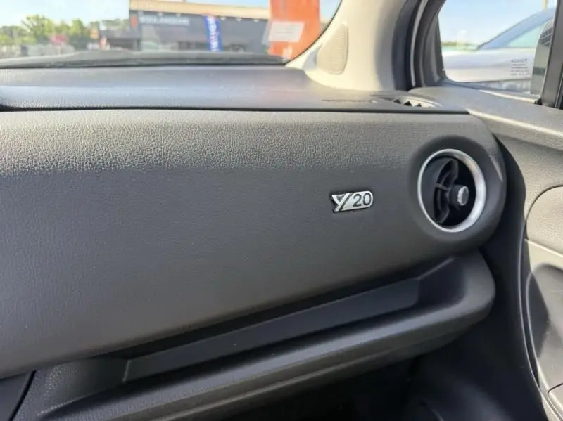 Détail de la planche de bord noire de la Toyota Yaris 2020 avec logo Y20 et sortie d'air ronde côté droit.