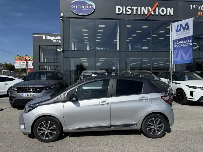 Toyota Yaris 2020 gris métal vue de profil côté gauche, toit et rétroviseurs noirs, devant un concessionnaire Distinxion.