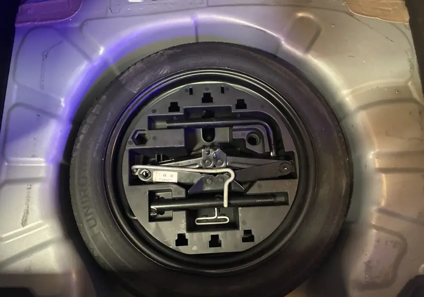 Gros plan sur la roue de secours et les outils de bord dans le coffre d'une Renault Clio 1.5 BlueDCI Business gris 2022.