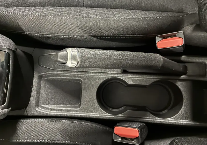 Vue plongeante sur la console centrale noire de la Renault Clio 1.5 BlueDCI Business 2022, avec frein à main manuel et porte-gobelets.