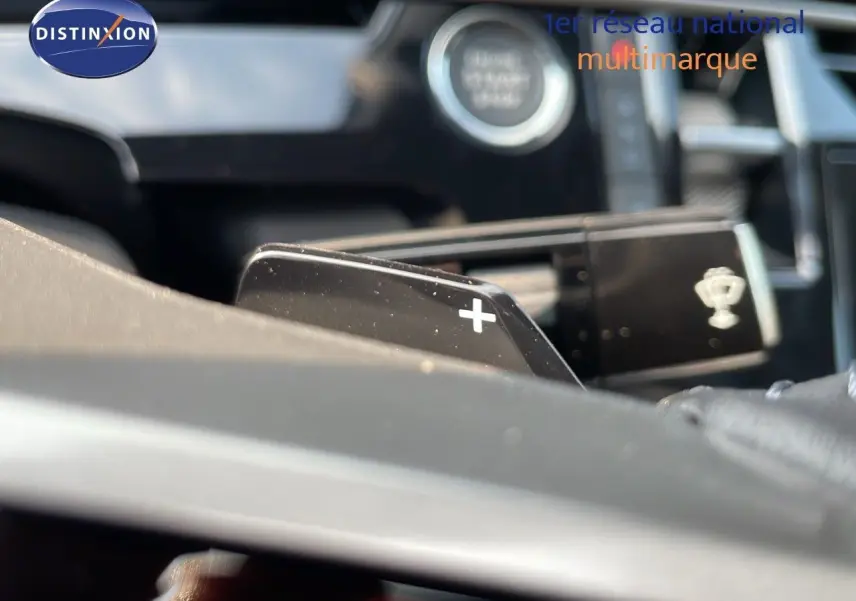 Gros plan sur la palette de changement de vitesses "+" du volant dans l'habitacle du Peugeot 3008 gris 2025.