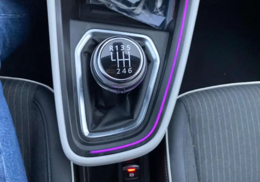 Le levier de vitesses manuel noir de la Renault Clio 2023 avec éclairage d'ambiance violet autour du console central.