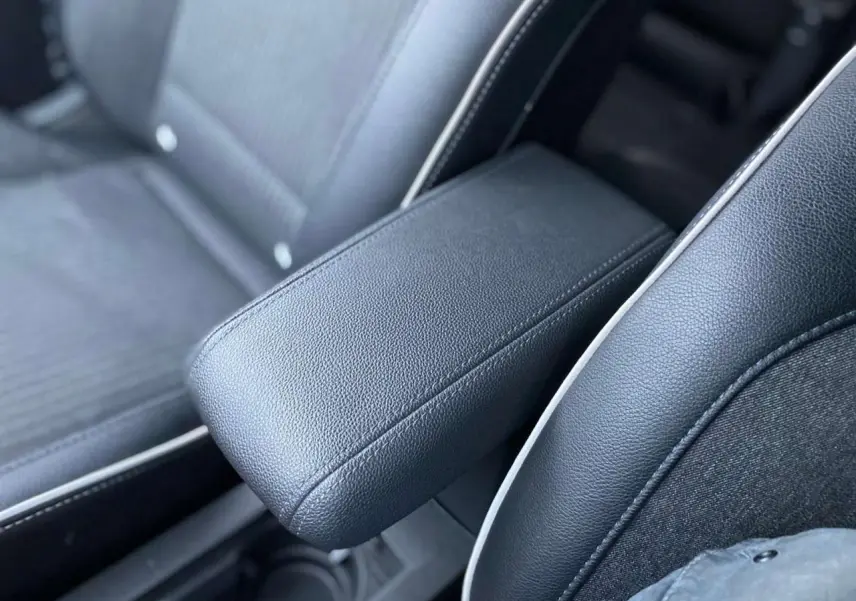 Accoudoir central en similicuir noir et tissu gris sur siège avant d'une Renault Clio 2023.