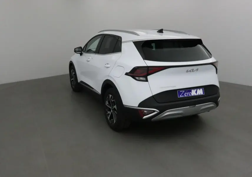 Vue 3/4 arrière droite du SUV KIA Sportage blanc 2025 avec feux arrière LED et jantes alliage noires.