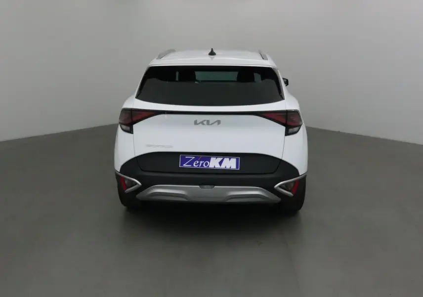 Vue arrière d'un Kia Sportage blanc 2025 avec feux arrière en bandeau et plaque Zero KM.