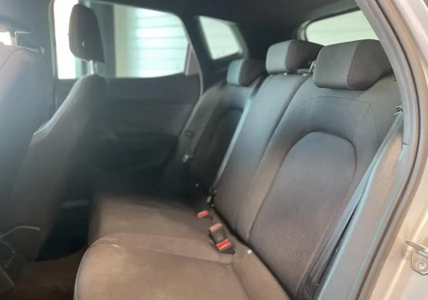 Vue intérieure côté droit sur la banquette arrière noire textile du SEAT Arona 2024 avec appuie-têtes et ceintures visibles.