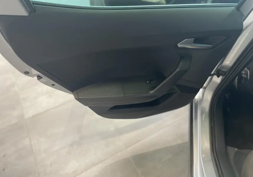 Vue intérieure de la porte avant gauche noire du SEAT Arona 2024 avec poignée argentée et bouton de lève-vitre.