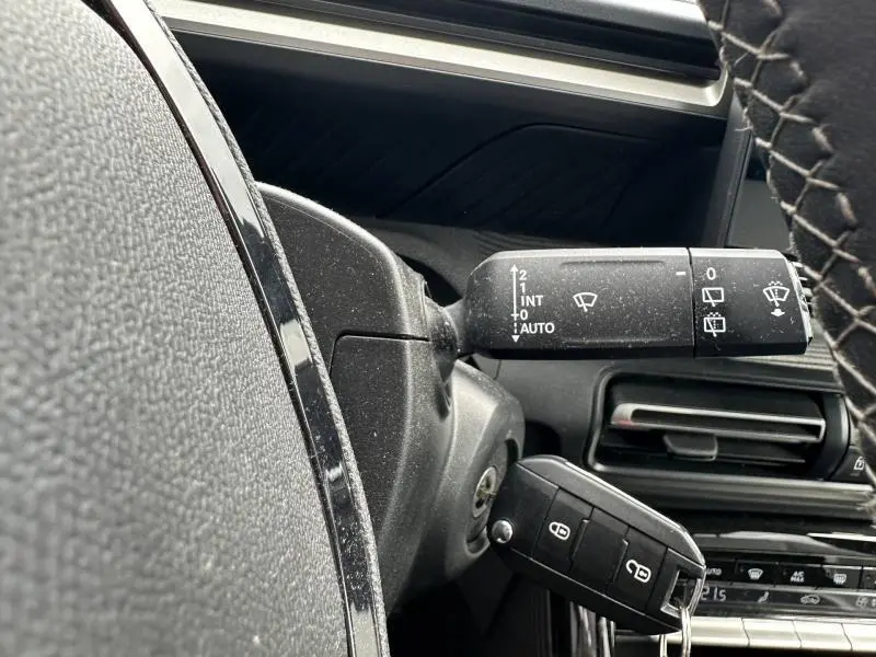Gros plan sur la commande d’essuie-glace et clé dans le contacteur d’une Citroën C3 2025 gris Mercury, intérieur noir.