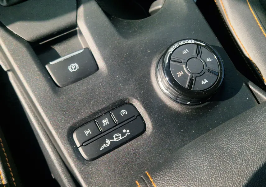 Gros plan sur la molette de modes de conduite et les boutons de contrôle du Ford Ranger Wildtrak, intérieur noir avec surpiqûres orange.