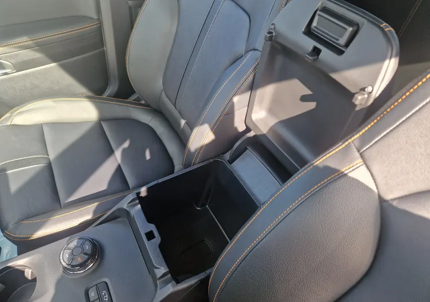 Vue rapprochée de la console centrale ouverte et des sièges en cuir noir avec surpiqûres orange du Ford Ranger Wildtrak 2025.
