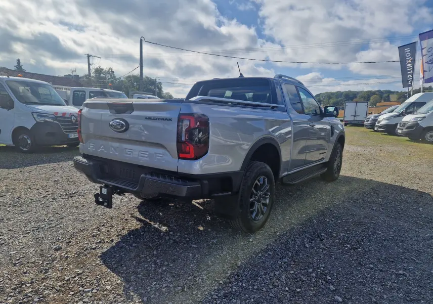 Ford Ranger Super Cabine gris iconic vu en 3/4 arrière droit, avec benne protégée et attelage visible.