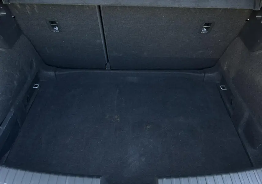 Vue plongeante sur le coffre spacieux et tapissé de noir du SEAT LEON 2.0 TDI 150 DSG Style gris argent 2024.