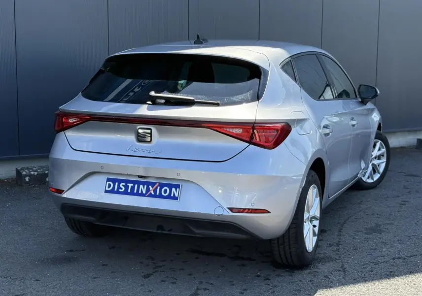 Vue 3/4 arrière droite d'une SEAT Leon gris argent avec vitres arrière surteintées et feux arrière LED.